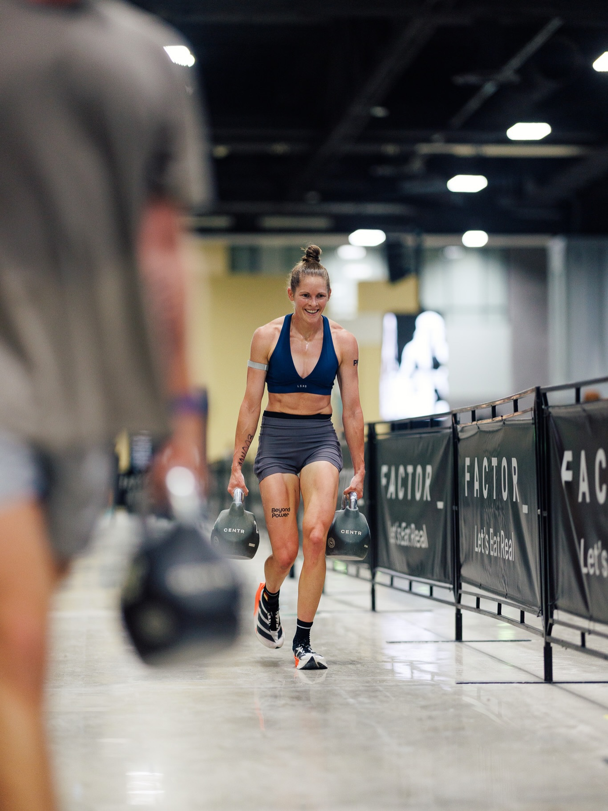 Runner's calves and quads mid-stride during a Hyrox run, right after finishing a heavy station